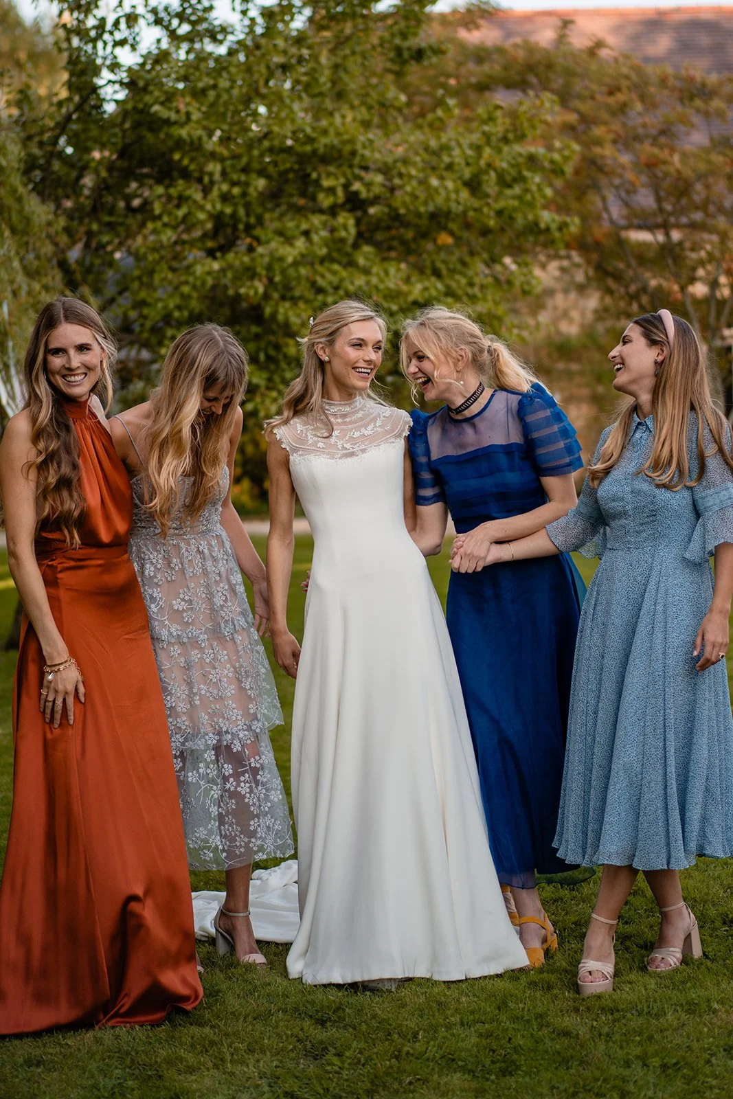 Bride standing outdoors with friends in colourful dresses at a wedding celebration