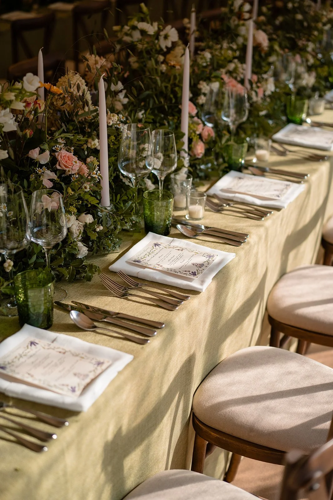 Wedding reception table with floral arrangements, candles, menus and place settings