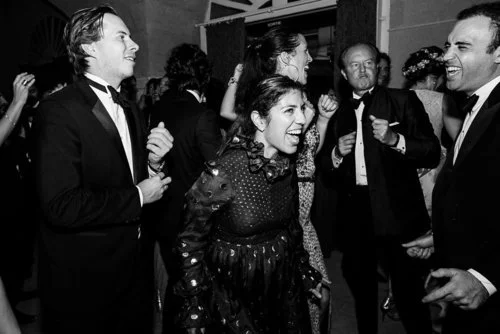 Wedding guests dancing and laughing on a crowded dance floor during the evening reception