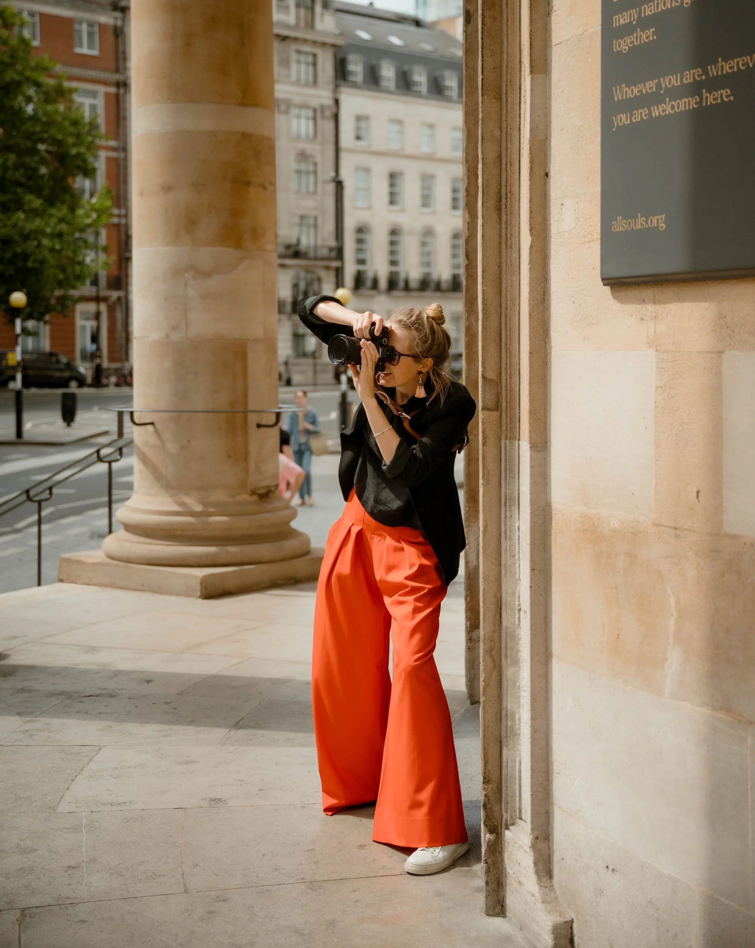 Female photographer in orange trousers photographing a wedding with a Sony camera.