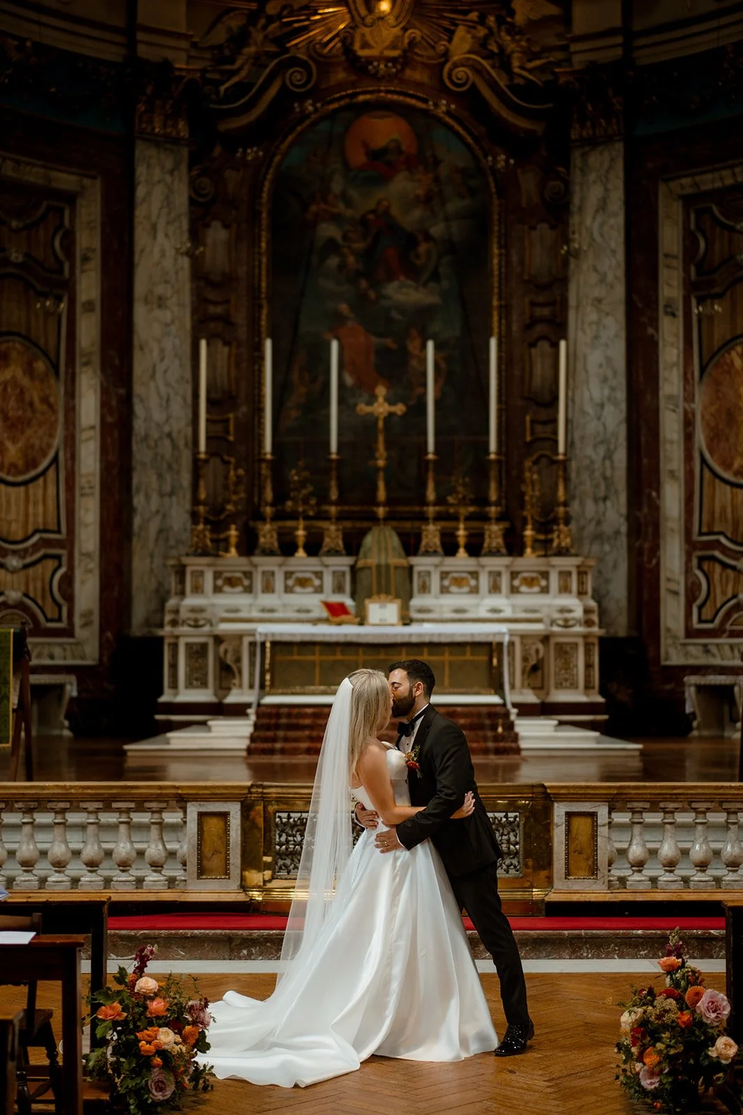 Bride and groom kissing during a wedding ceremony inside a historic church.