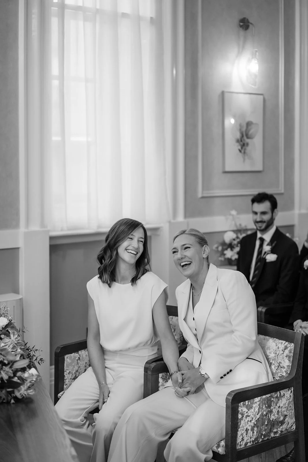 Two women laughing during wedding ceremony at Marylebone Old Town Hall London
