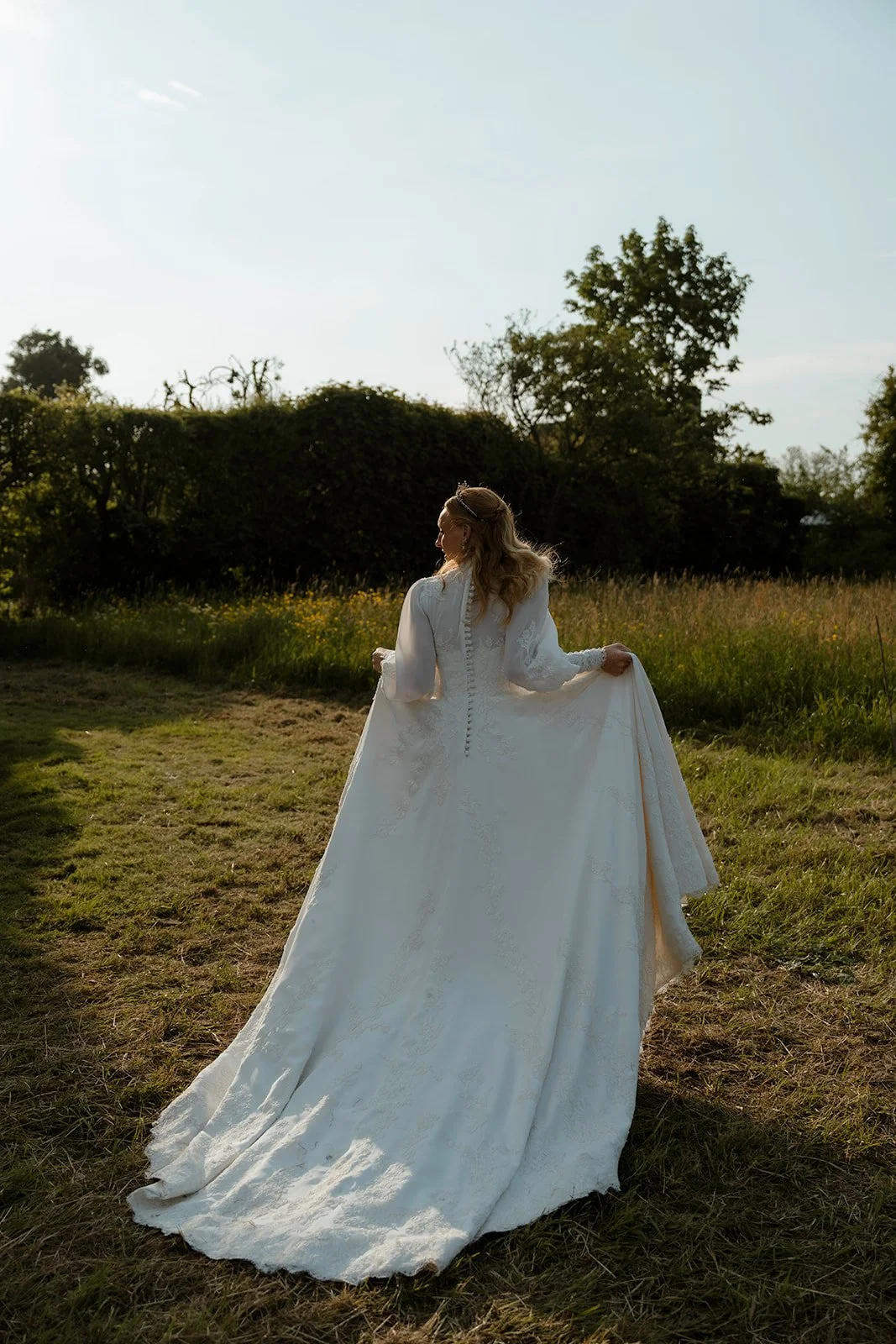 Bride walking through a field at golden hour showing movement and shape of the wedding dress.
