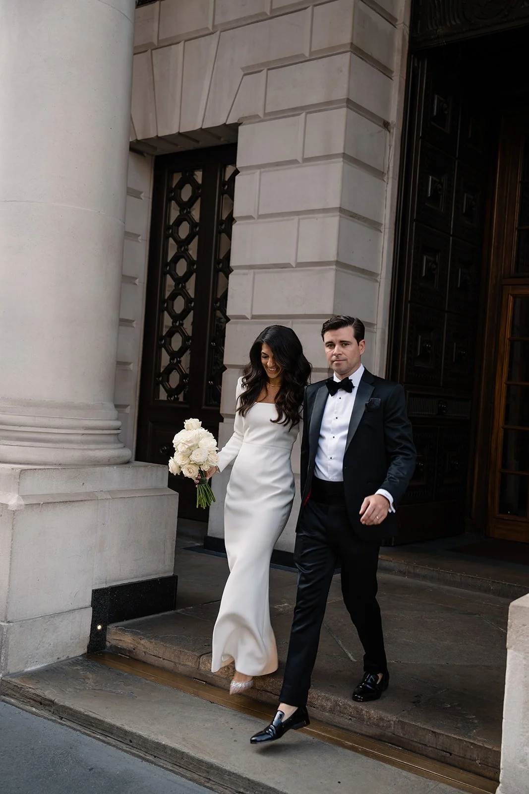Bride and groom leaving The Ned in London after their wedding ceremony, captured by London wedding photographer Helen Abraham. Elegant modern city wedding portrait.