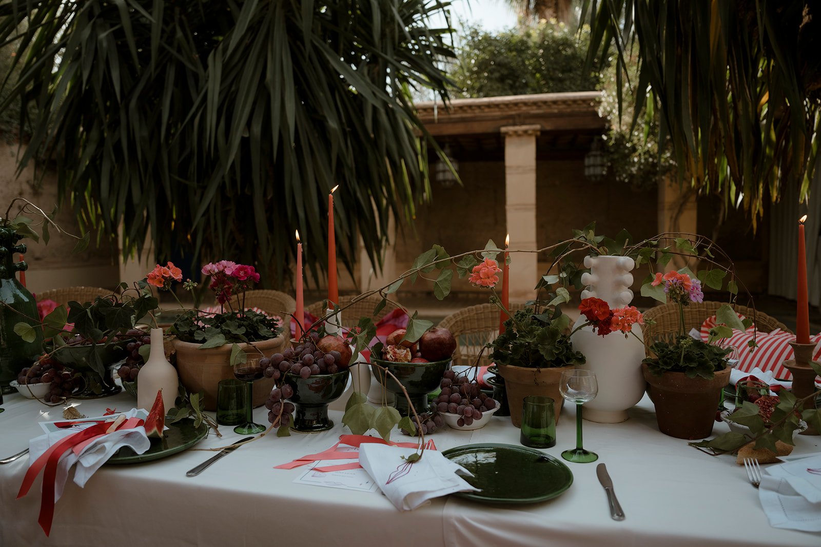Outdoor wedding table set with candles, fruit, flowers and terracotta pots in the garden courtyard at Hotel Les Deux Tours in Marrakech.