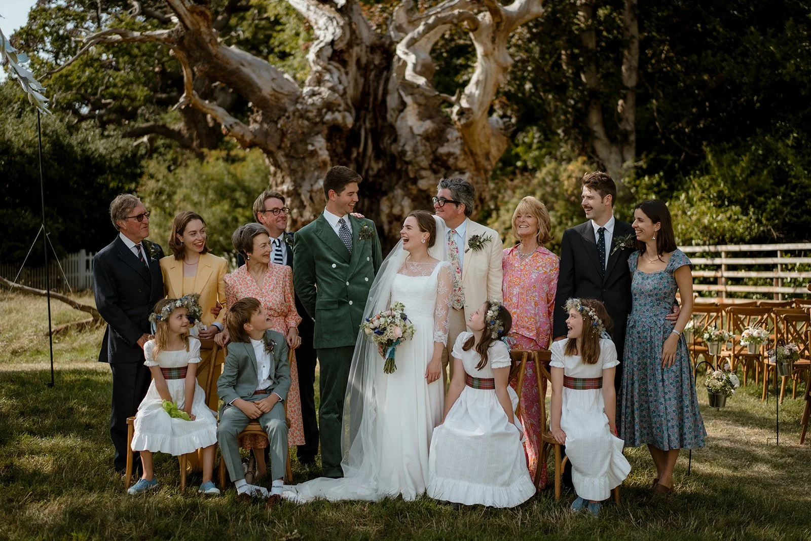 Bride and groom with parents and children in an outdoor family group photo at a wedding ceremony venue.