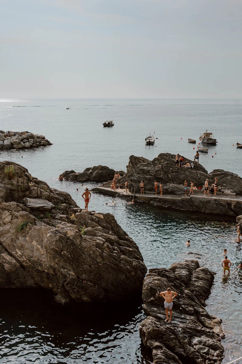 People swimming and sunbathing in Manarola harbour