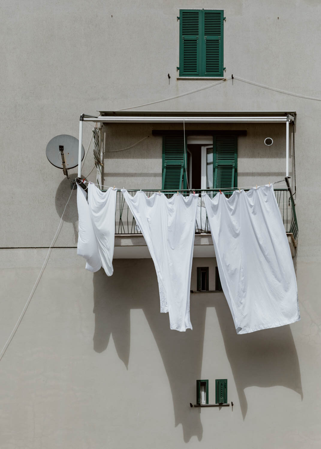 White sheets drying in the wind - green windows