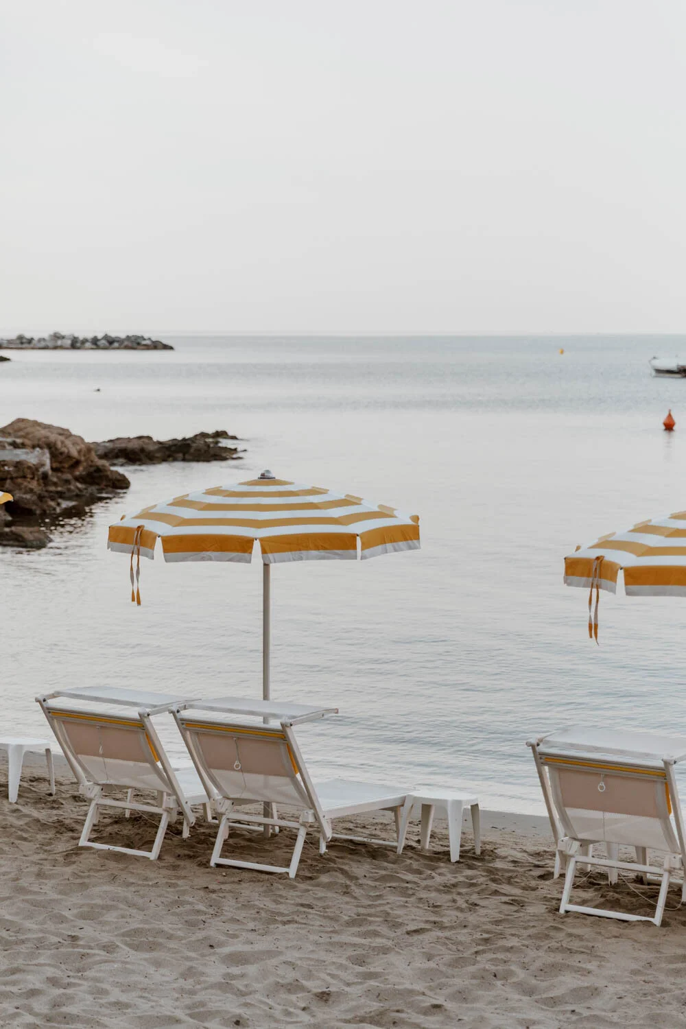 yellow and white parasol with deck chairs on private beach of hotel helvetia