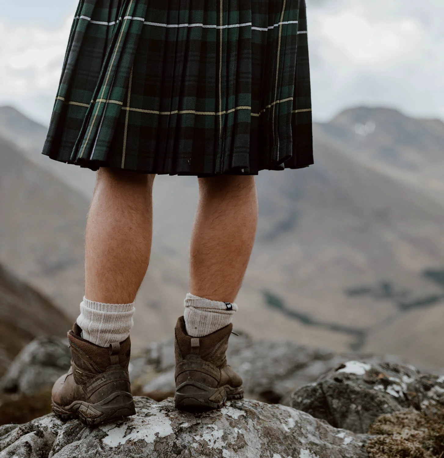 man stands on rock in kilt
