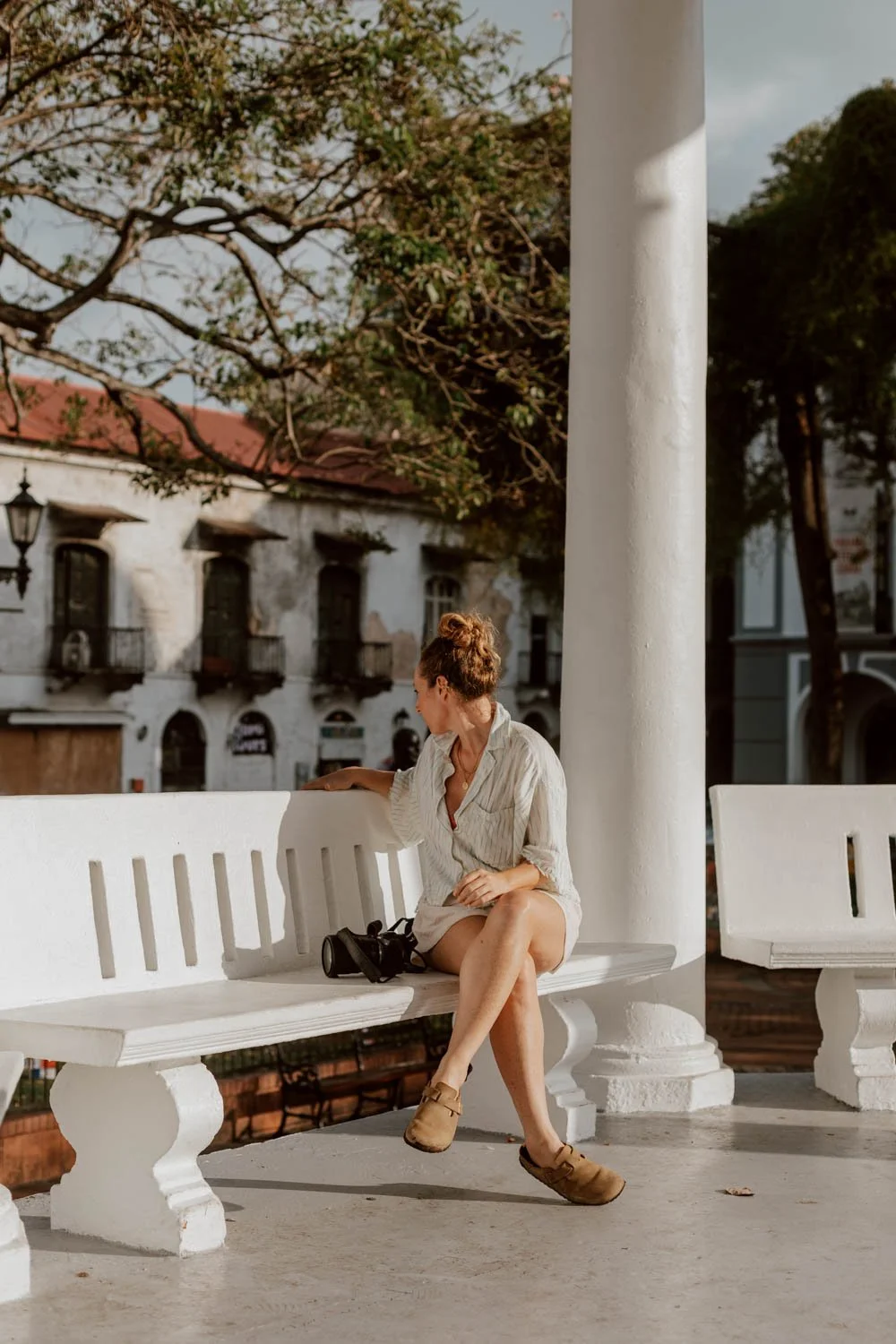 Woman sits on white stone bench in Plaza Simón Bolívar