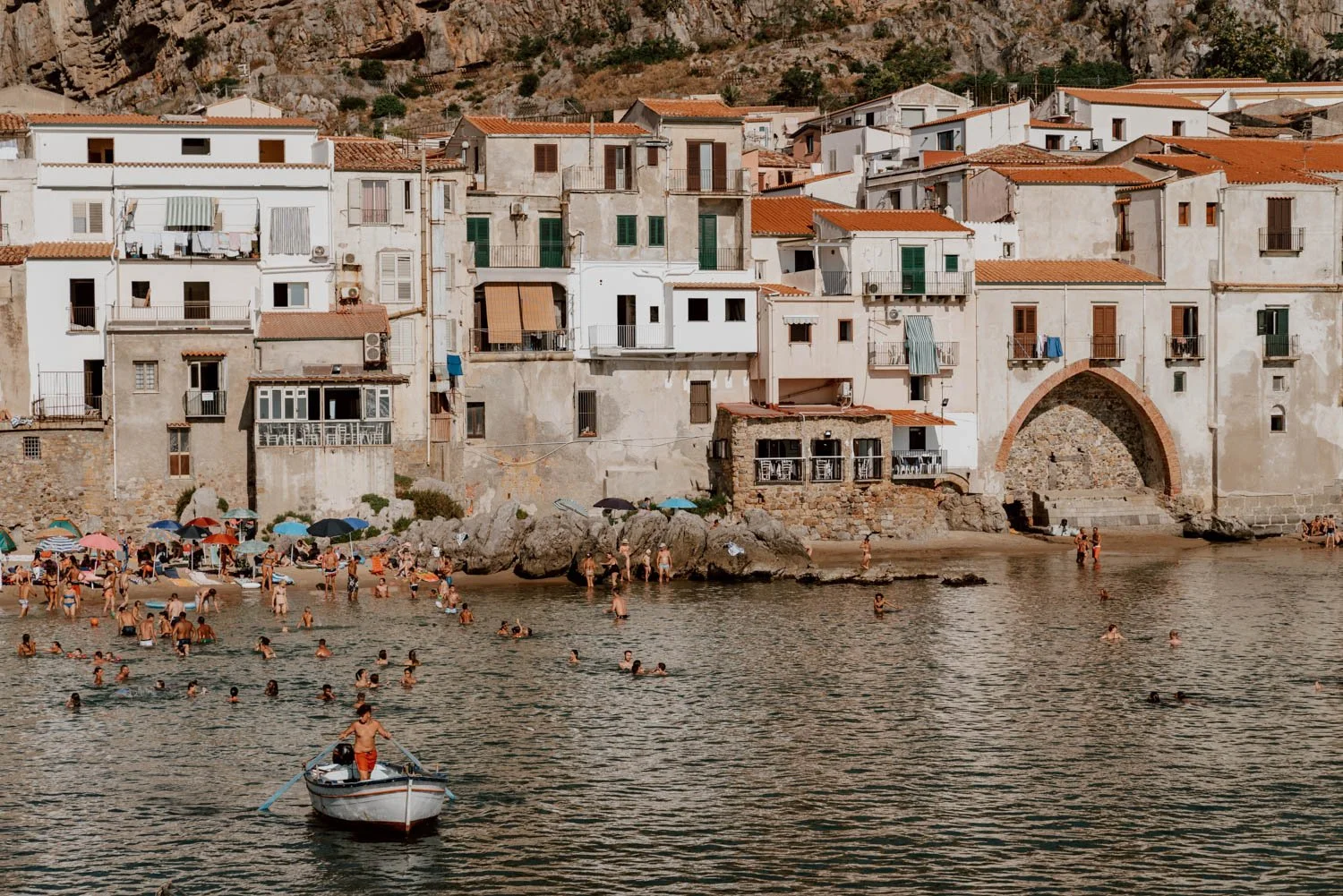 people swimming in Cefalu harbour during summer