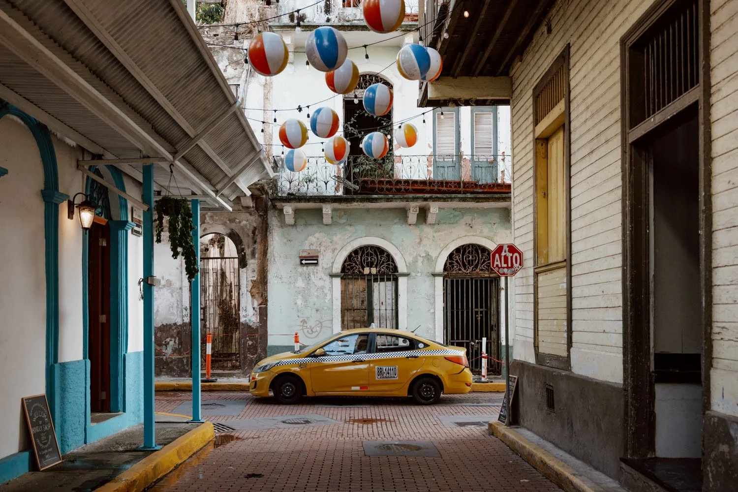 street in casco viejo with mix of clapperboard and concrete front buildings, with yellow taxi passing by