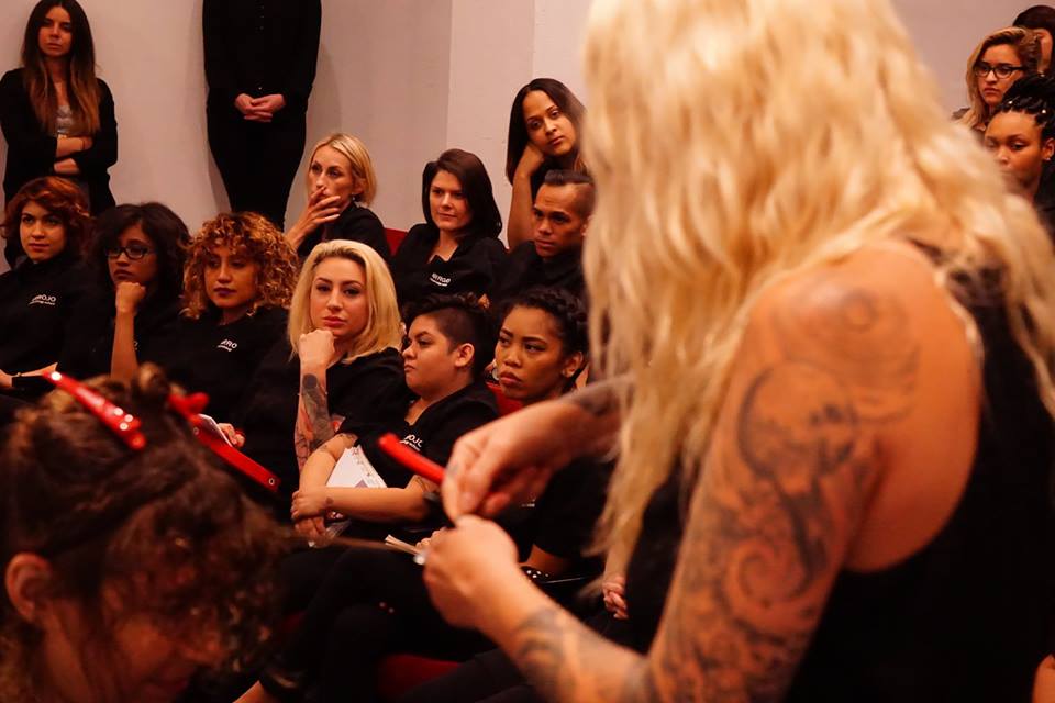 Students look on as Amanda Jenkins razor cuts some curls. 