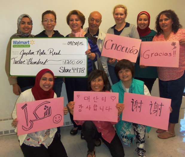 Joplin NALA Read students pose with the check from the Walmart Community Grant Program awarded from the Neighborhood Market Store #4478. The students hold signs that read "thank you" in their native languages.