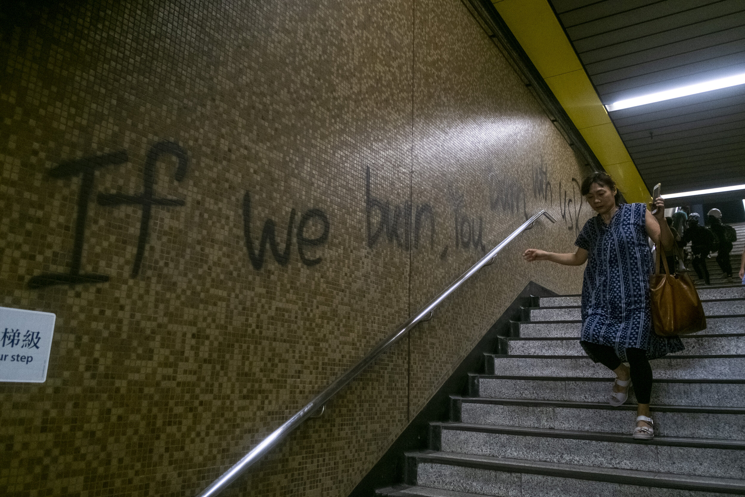  A woman walks past a spray painted slogan reading ‘If We Burn You Will Burn With Us!’ at the Kowloon Bay Metro Station on August 24, 2019. After heavy clashes between police and pro-democracy protesters, sporadic clashes and protests sparked up as p