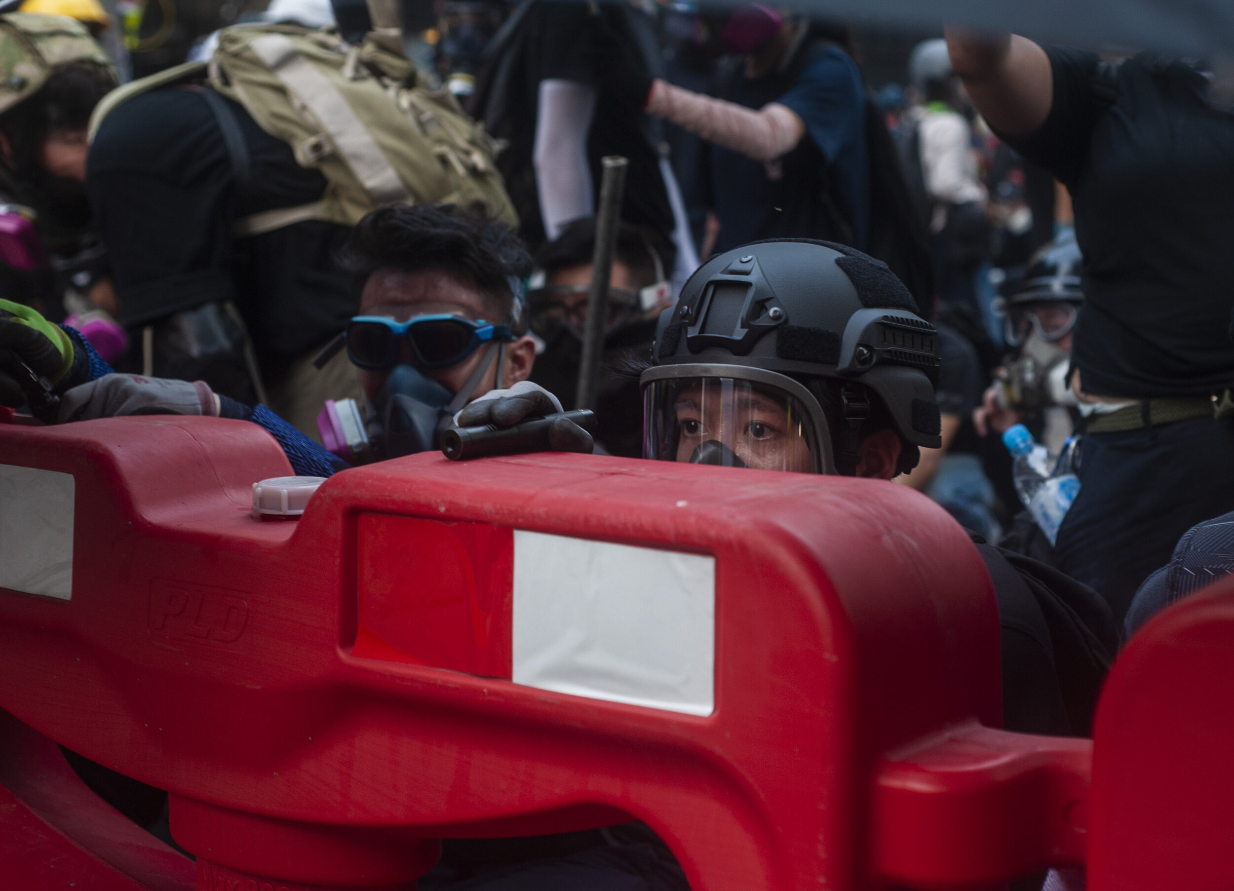  A pro-democracy protester peers over a makeshift barricade at advancing riot police during a heavy clash in Kwun Tong on August 24, 2019.  