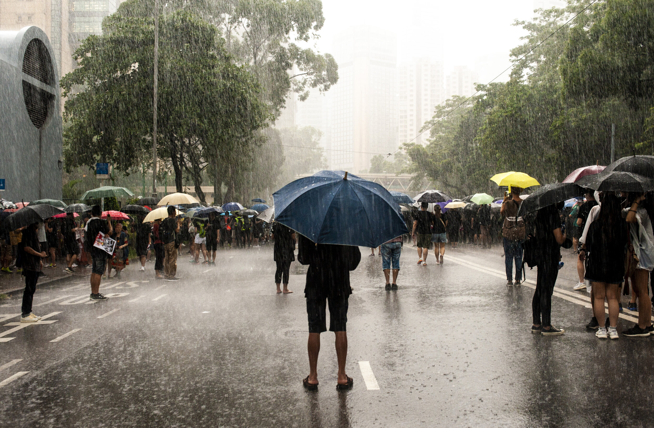  As the rain pours down, a man stands in the street as over 1 million people begin to take to the streets near Victoria Park and Causeway Bay on Hong Kong Island to protest police brutality and the extradition bill on August 18, 2019. 