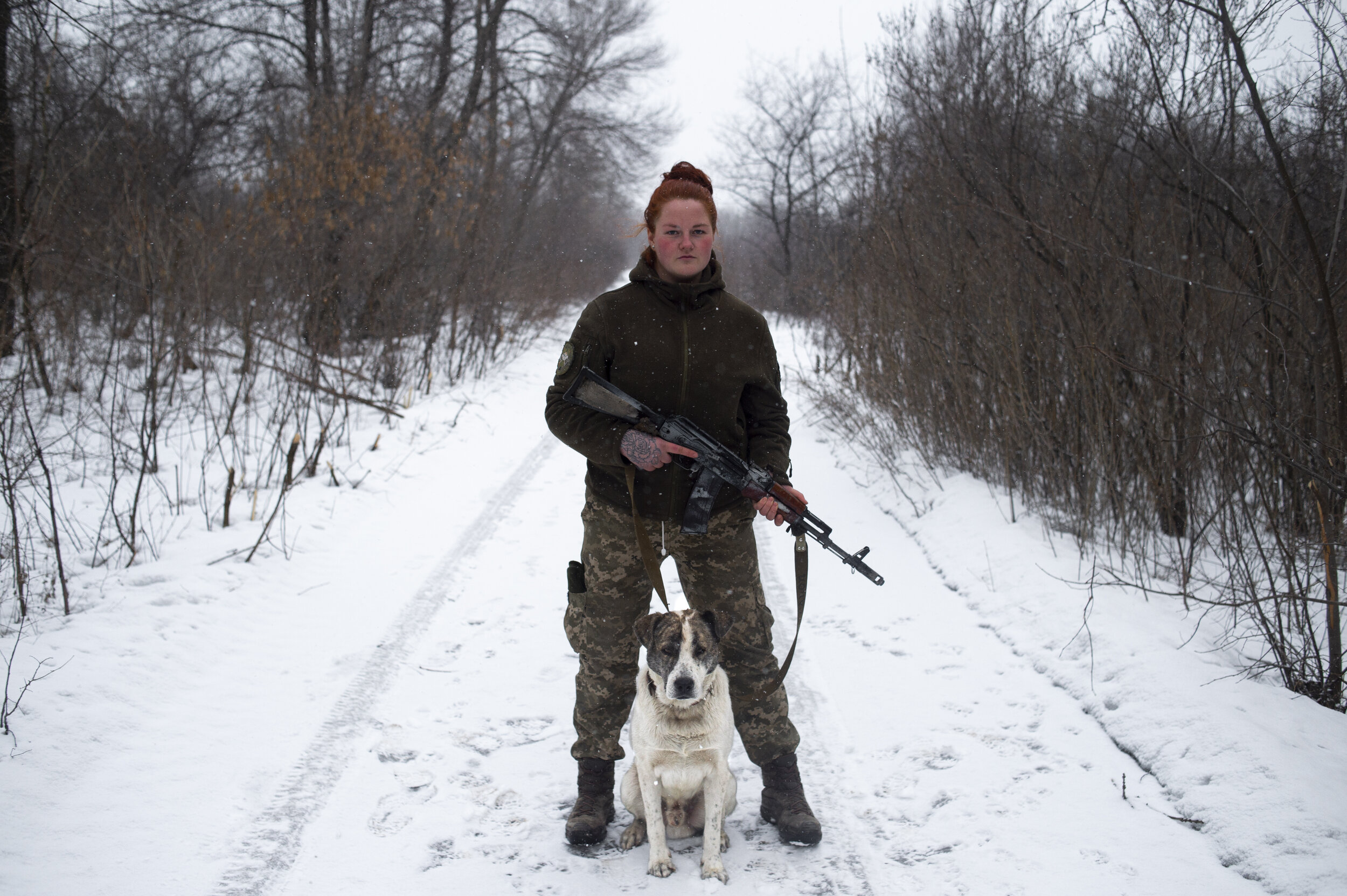  Katya Nalobina, a Ukrainian soldier in the 54th Mechanized Rifle Brigade, and her adopted dog Ser’Oga pose for a portrait in Zolote-4 near ‘Point Zero’ on February 25, 2019. Zolote-4 and ‘Point Zero’ as it is called by soldiers, is one of the most d