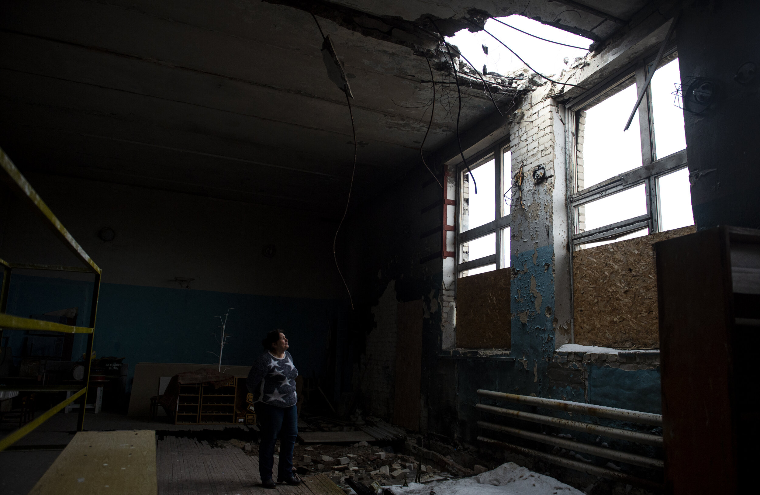  The principal of the school in Petrovsk examines a large hole in the gymnasium caused by an artillery shell. Despite attempts to keep civilian buildings such as schools and churches from being damaged the constant combat often results in some sort o