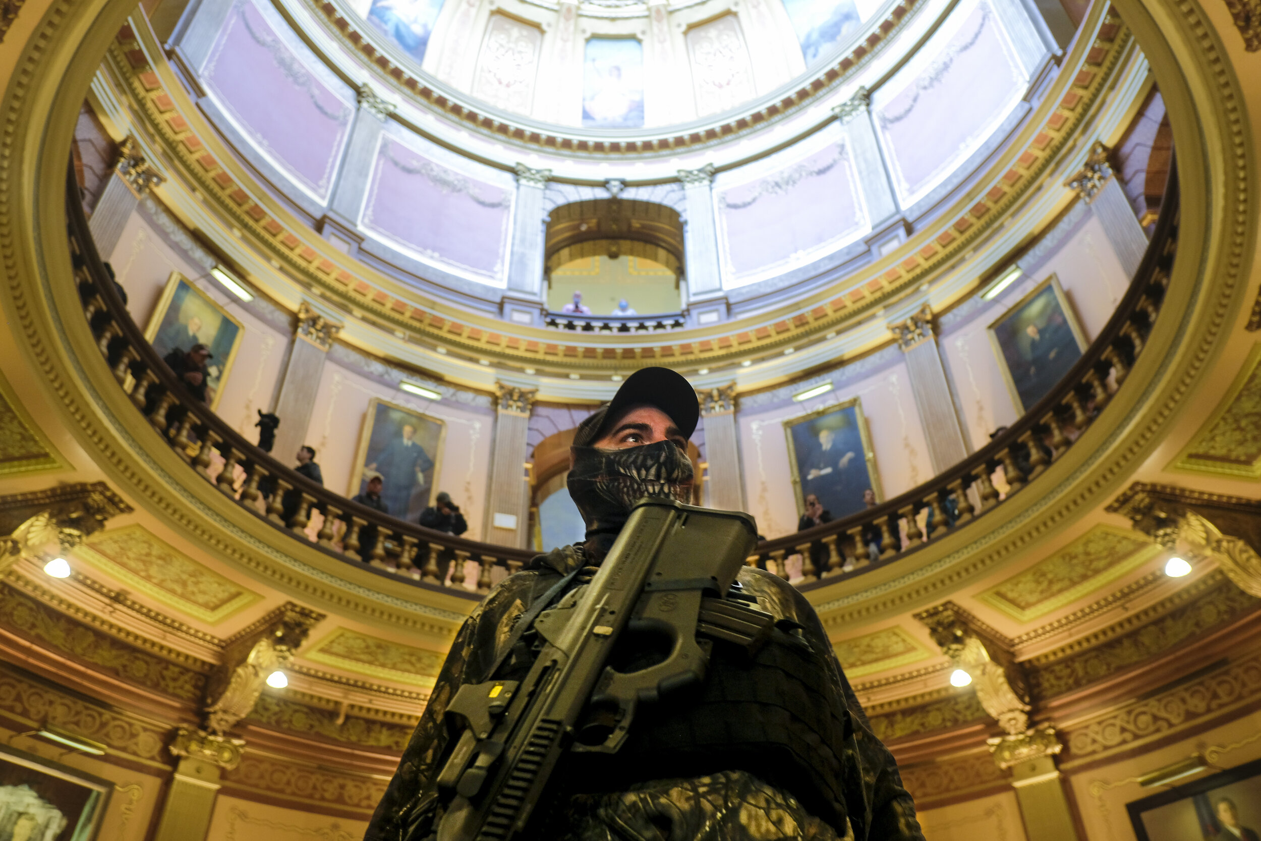  An armed member of a Michigan Militia group stands in the main rotunda of the Michigan Capitol Building as anti-lockdown protesters occupy the area outside the Senate Chamber during a large protest against Michigan Governor Gretchen Whitmer’s plan t