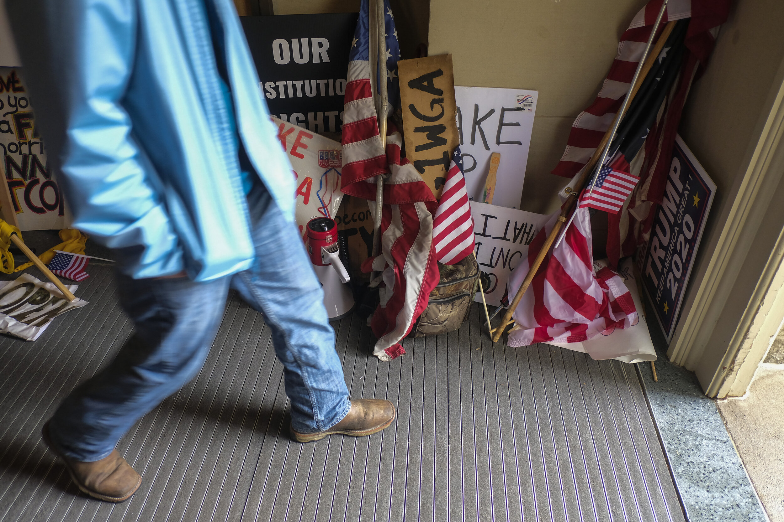  An anti-lockdown protester walks past American Flags and signs as he exits the Michigan Capitol Building after armed protesters and militia occupied the building in a call for Governor Gretchen Whitmer to end the state-wide Lockdown Order issued to 
