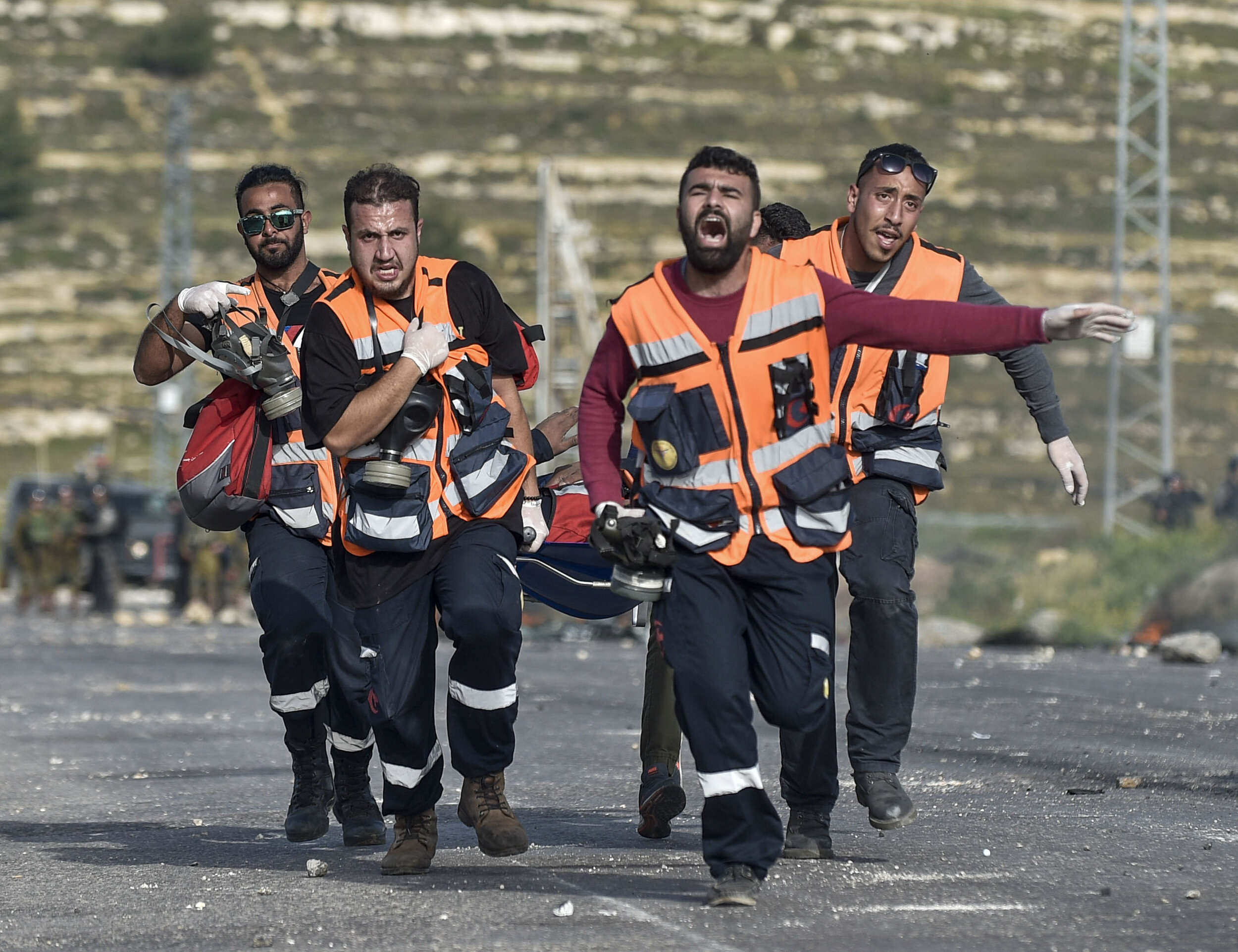  Members of a Palestinian medical team shout for assistance as they rush one of their own up the road after IDF soldiers shot a medic point-blank during heavy clashes near Beit-El in the Occupied West Bank.  