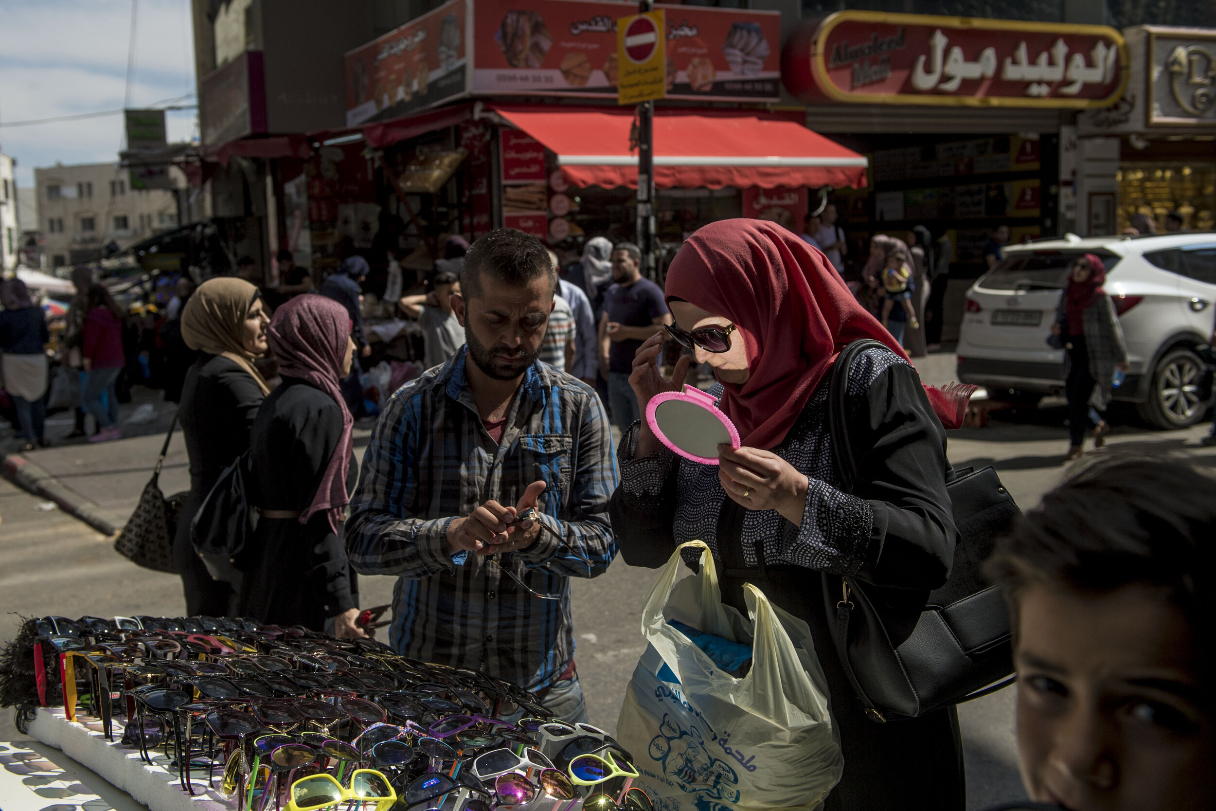  A Palestinian woman tries on sunglasses near Al-Minarra Square in Ramallah. Commercial retail has quickly taken over the economy of Ramallah which used to be dominated by farming. 