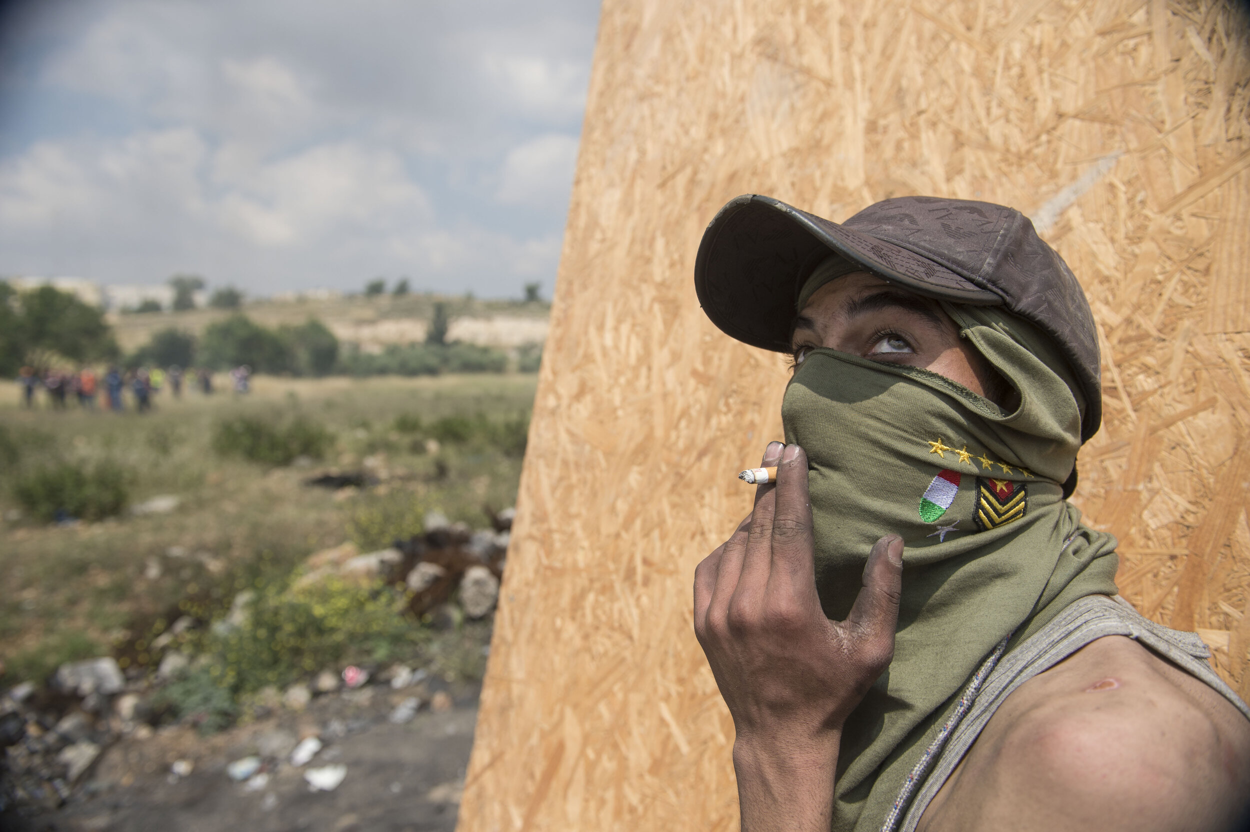  A Palestinian protester smokes a cigarette through his mask while taking cover from Israeli snipers during Nakba Day protests in Beit-El in the Occupied West Bank. 