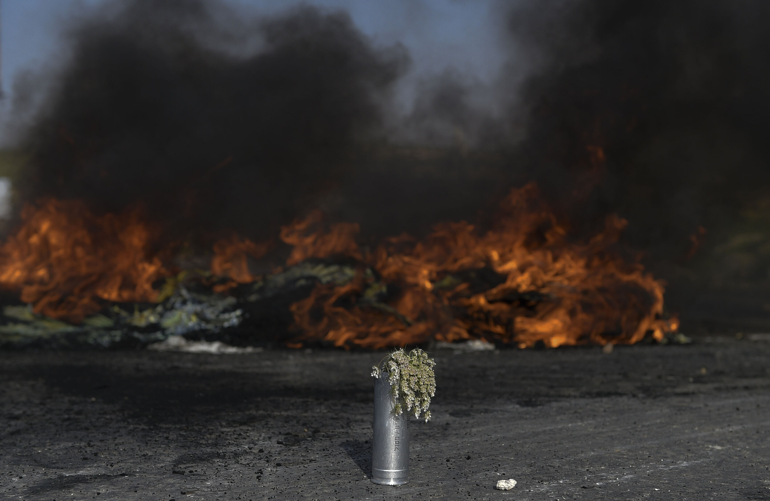  A teargas canister with flowers in it is placed in front of a tire fire during clashes at Beit-El in the Occupied West Bank. 