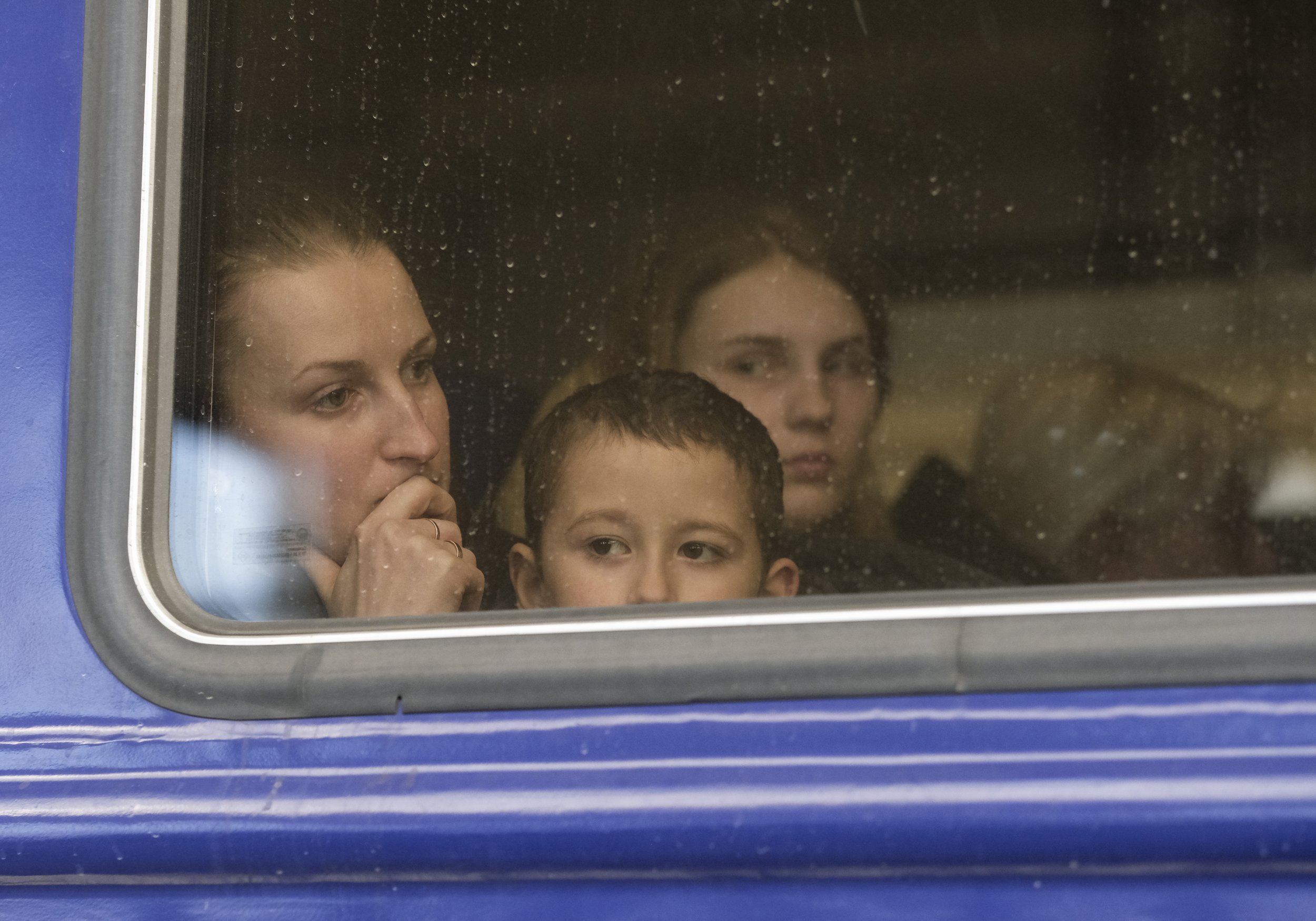  A woman and her children wait for their train to depart towards the Polish border from the Lviv-Holovnyi Railway station on March 12, 2022. Millions of Ukrainians fled to Poland, Romania, and other neighboring countries as Russian troops crossed the
