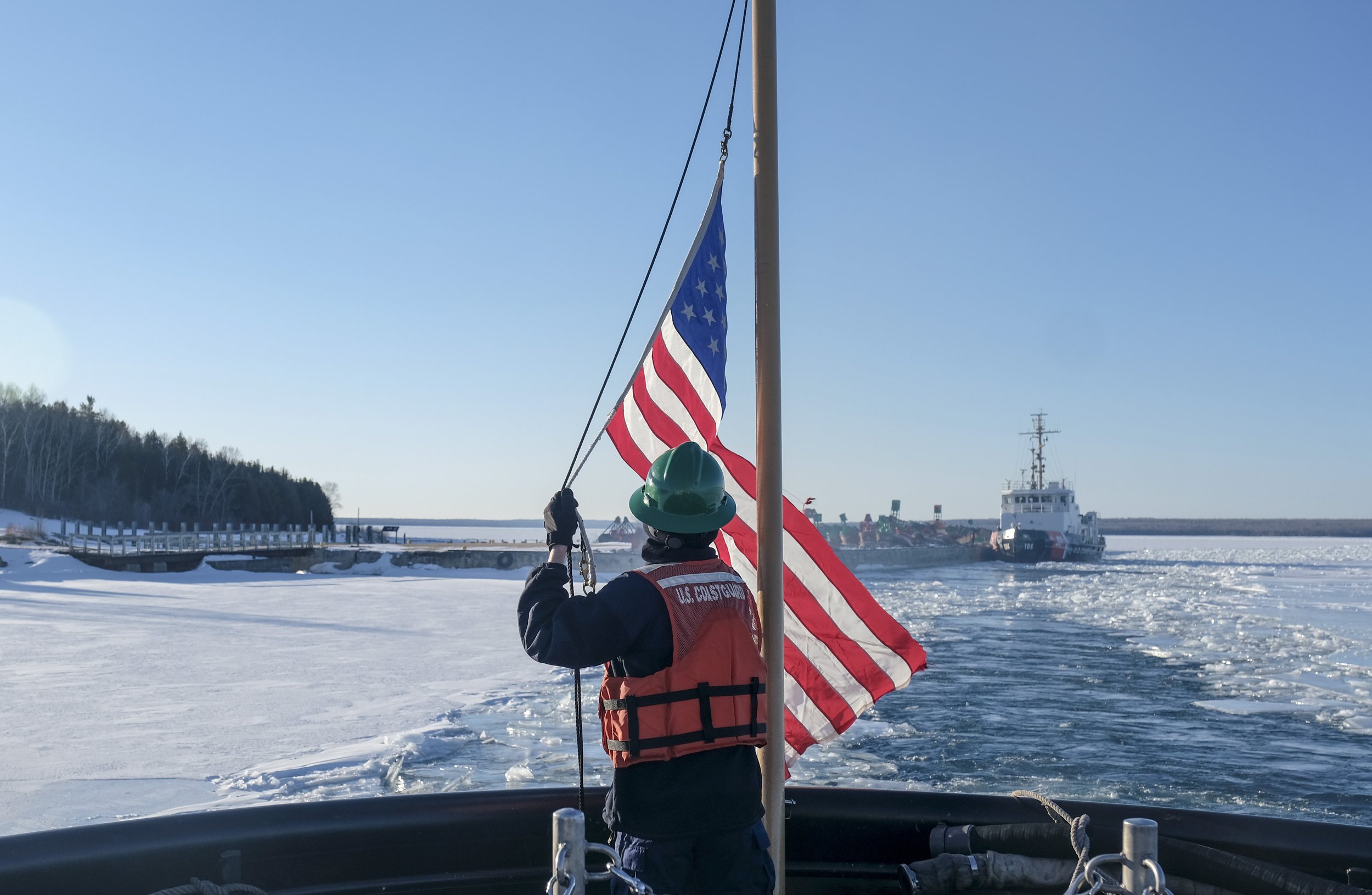  The flag is raised as the US Coast Guard Cutter ‘Katmai Bay’ departs its overnight mooring and resumes operations on Lake Huron during Ice Breaking operations on March 13, 2023.  