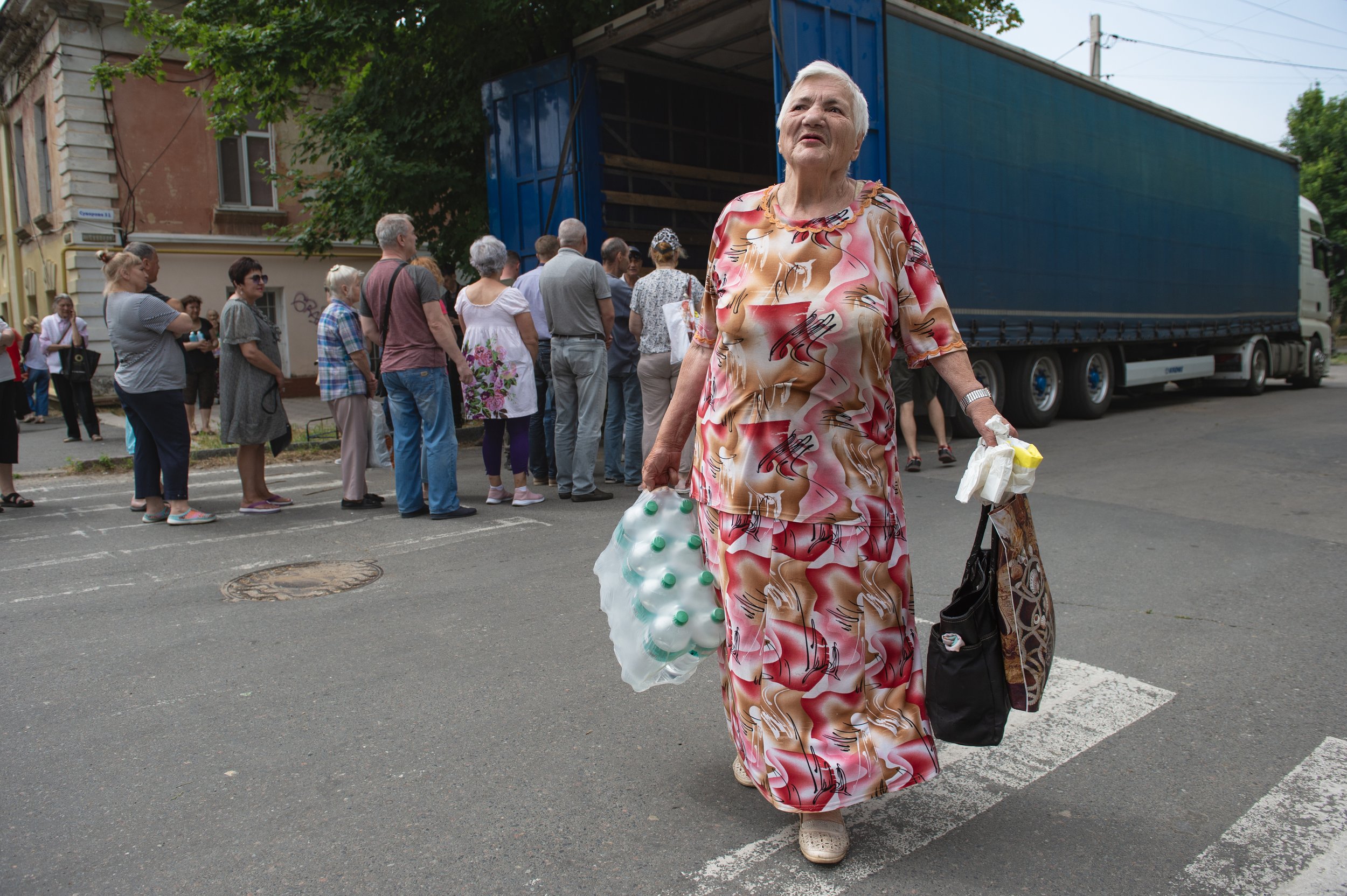  A woman holding bottled water and food listens to the sound of artillery fire as Ukrainians line up to collect aid in Kherson, Ukraine on June 8, 2023. Kherson continues to see intense fighting as Ukrainian forces and Russian troops battle each othe