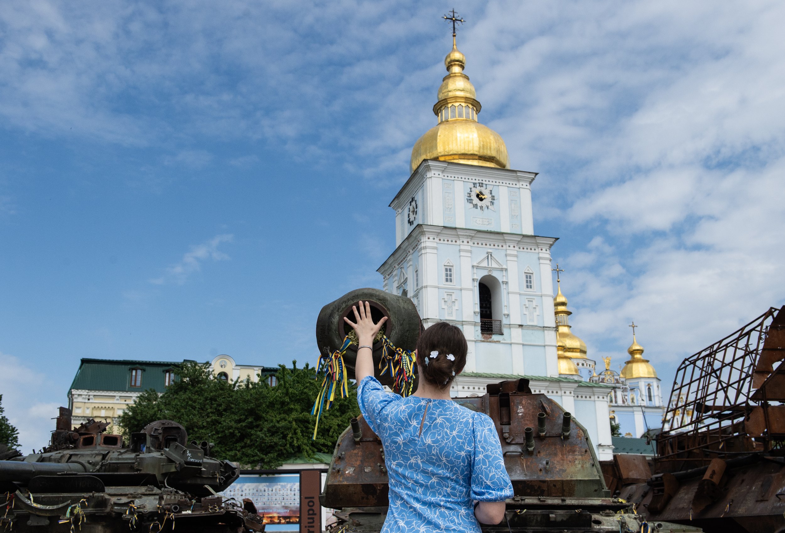  A woman places her hand over the muzzle of a mobile artillery piece on display at an open-air museum of Russian military equipment in Kyiv, Ukraine. Pieces in the display come from battlefields all over Russia and include tanks, APCs, drones, grenad