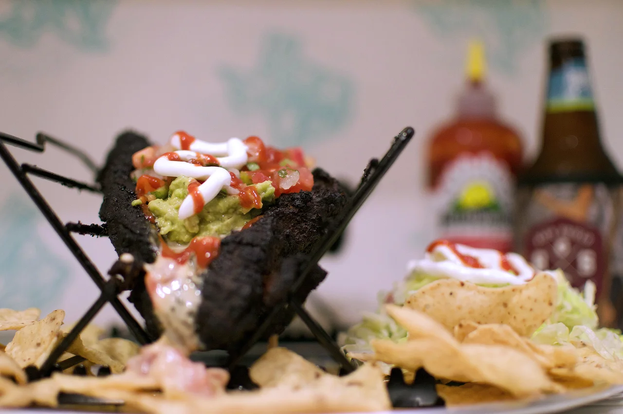 Dressed with queso, guacamole, pico de gallo, sour cream, Yellowbird sauce, and some lettuce on the side.