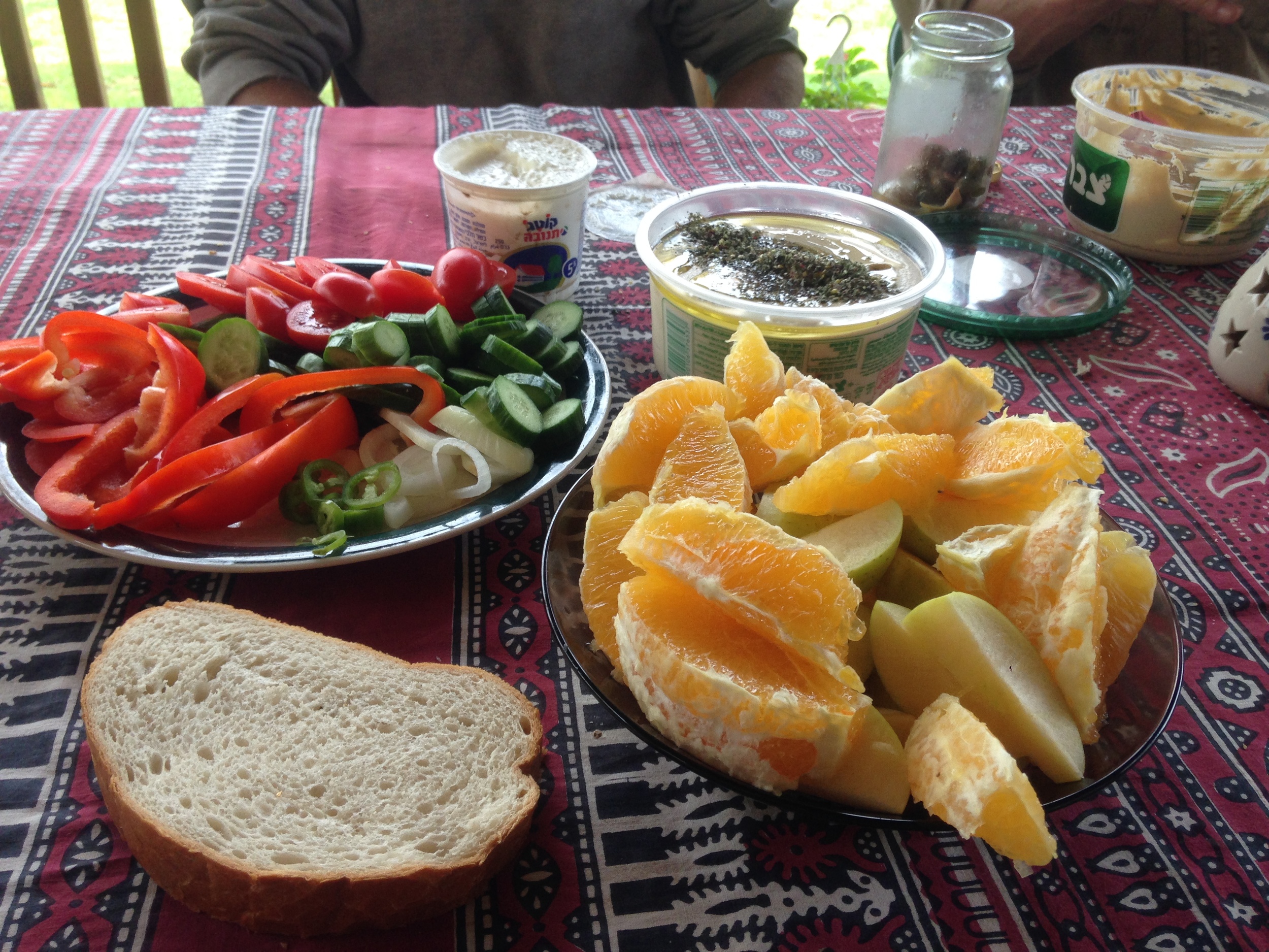 Our bountiful breakfast consisting of: bread, hummus, cottage cheese, olives, peppers, cucumbers, tomatoes, onions, hot peppers, oranges, and apples.