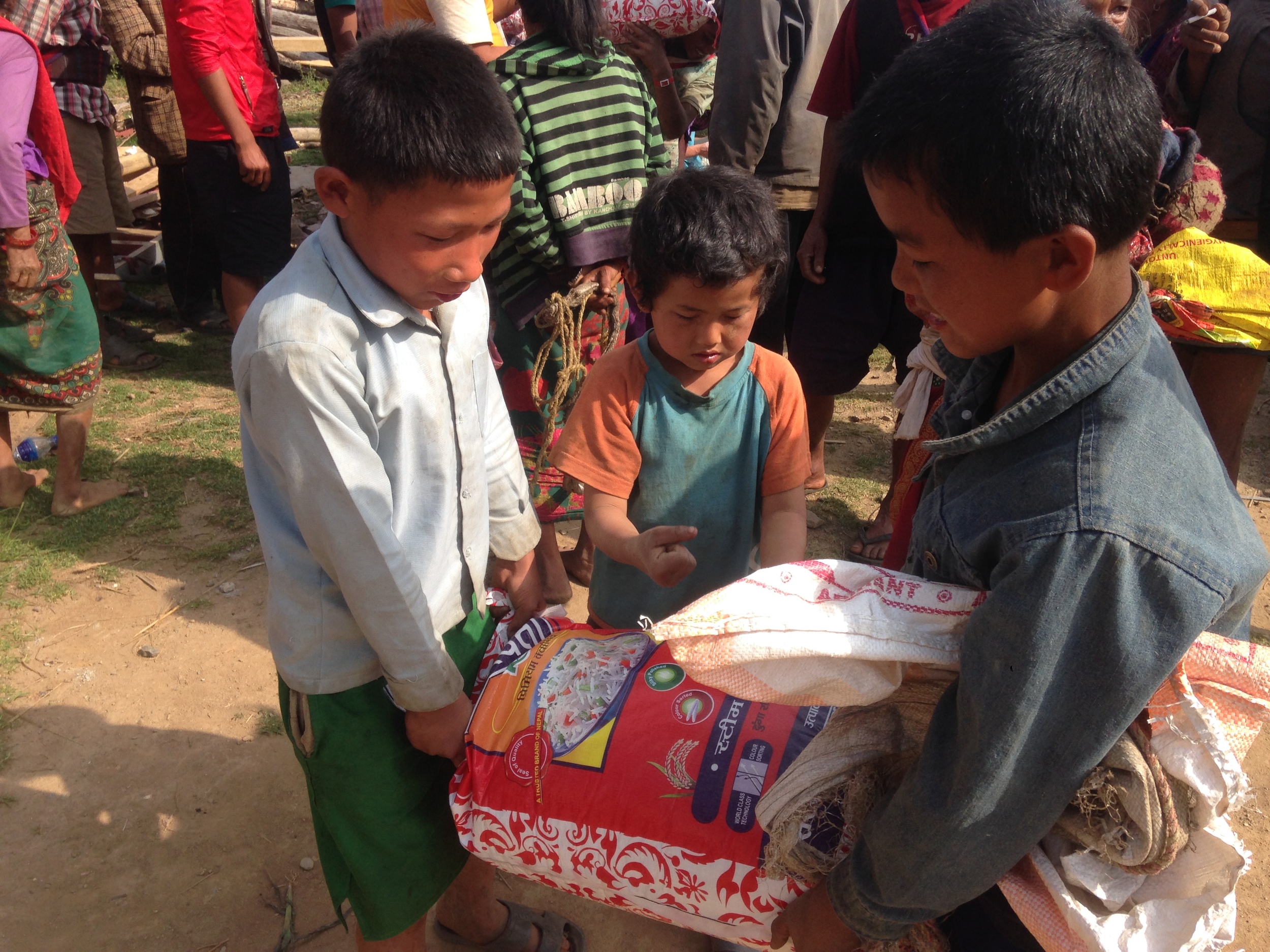  Boys work together to carry rice back to their household. 