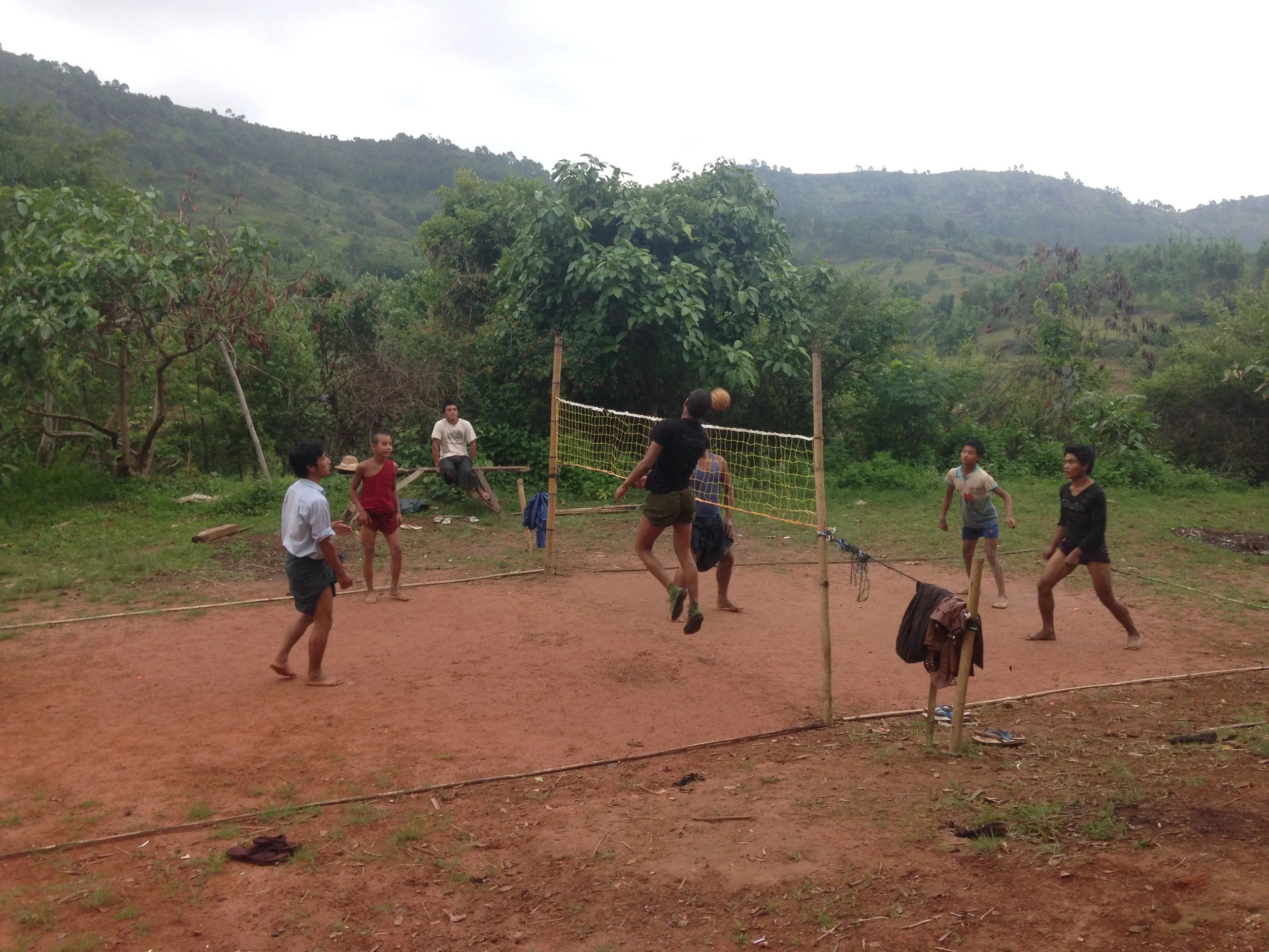 Kids playing caneball outside a village.