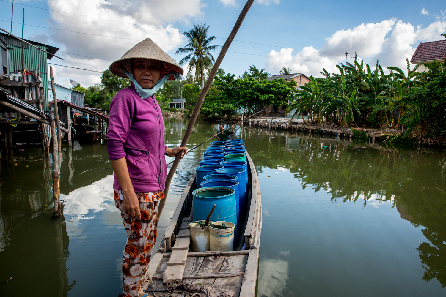  Woman on boat full of barrels of water to be sold to drought ravaged farmers in Soc Trang, Mekong Delta, Vietnam. 