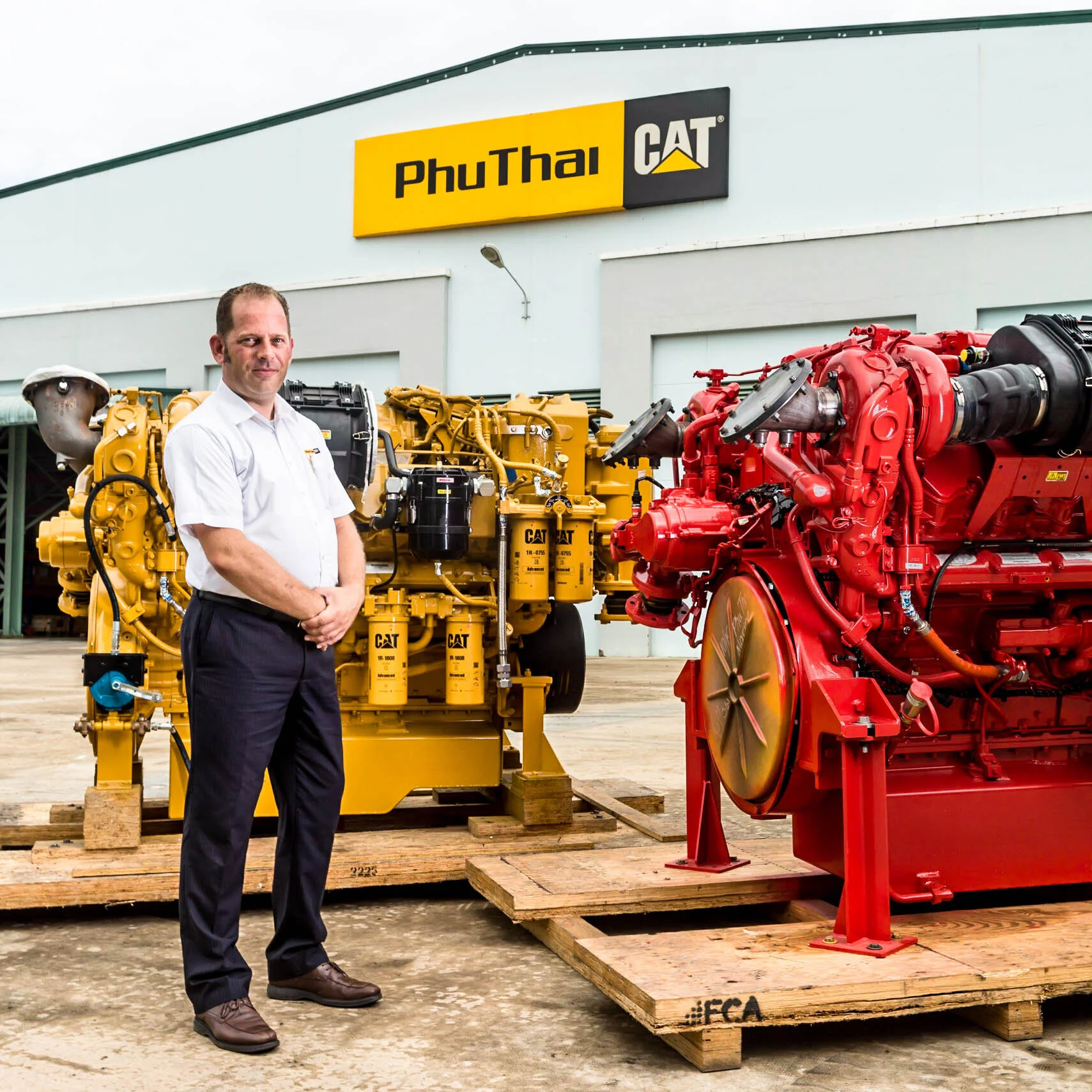  Portrait of man with PhuThai Cat diesel and gas industrial engines at factory. 