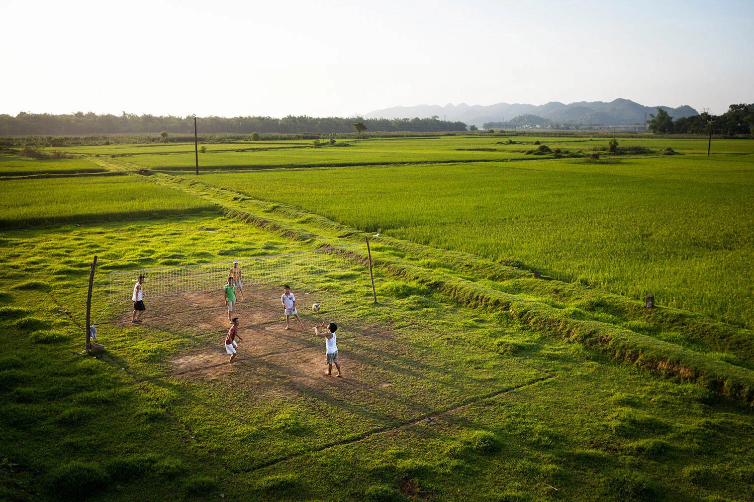  Young men play volleyball in a dirt field amongst rice fields near Vinh, Vietnam. 