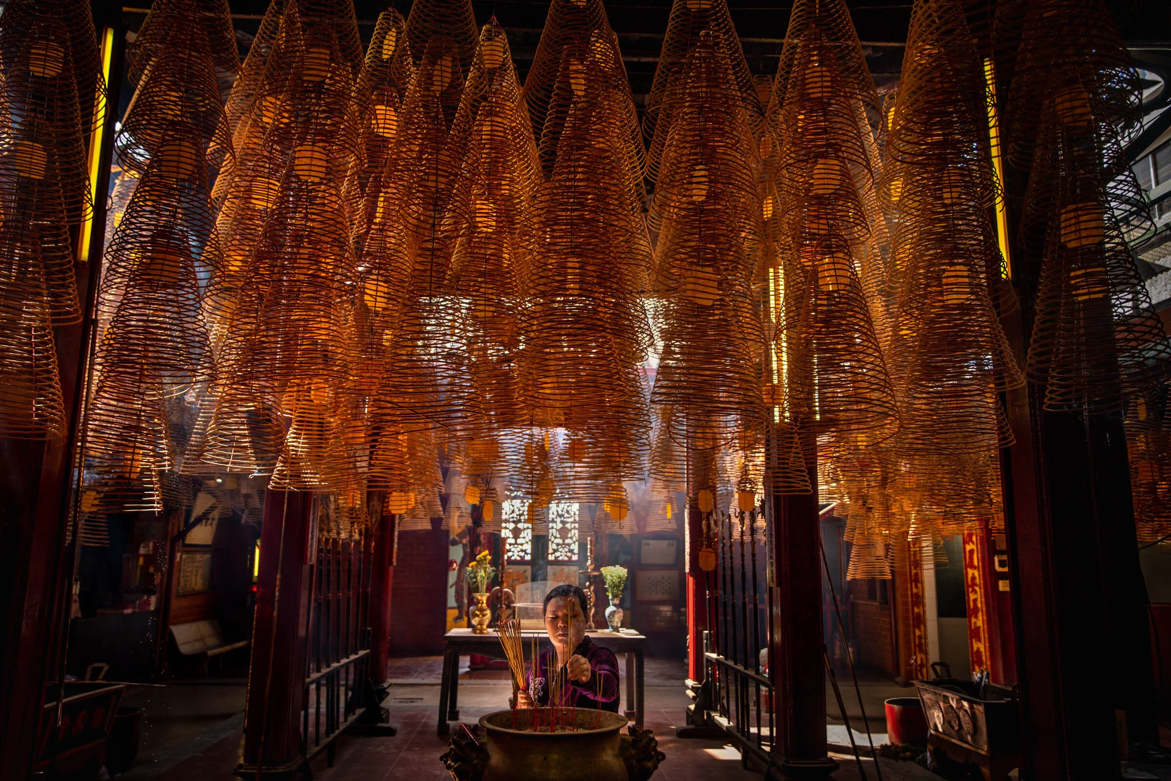  A woman places incense on the alter as giant incense coils burn above at Ong Temple, Can Tho, Vietnam. 