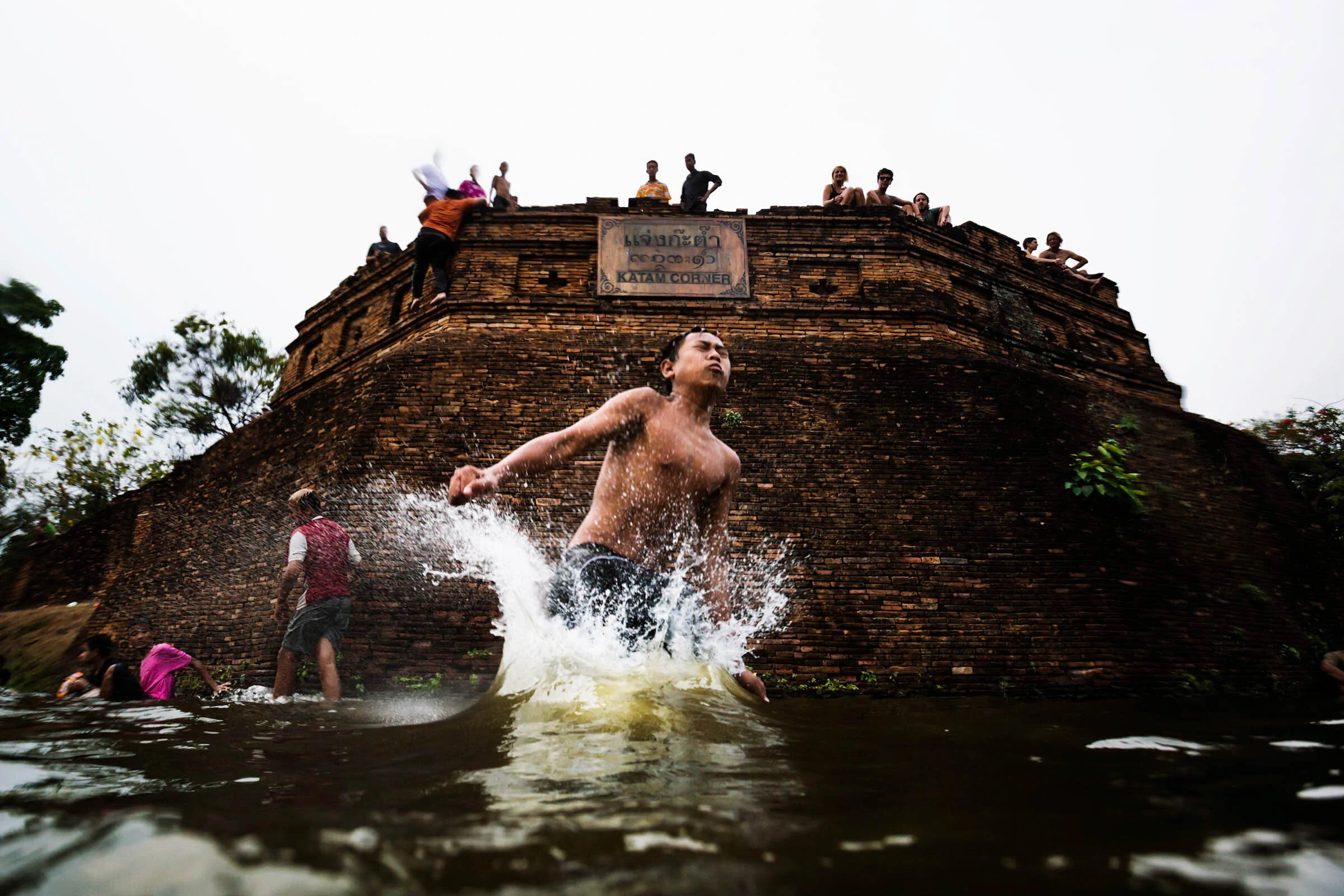  Water splashes as Asian boy lands Chiang Mai moat during Songkran New Years Water Festival, Thailand. 