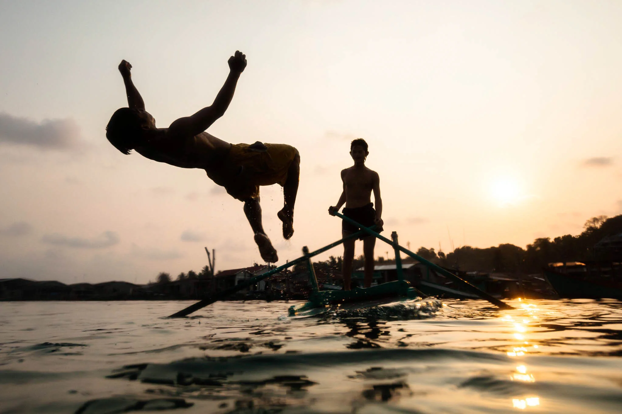  Young man back flips from raft at sunset in Koh Sdach, Cambodia. 
