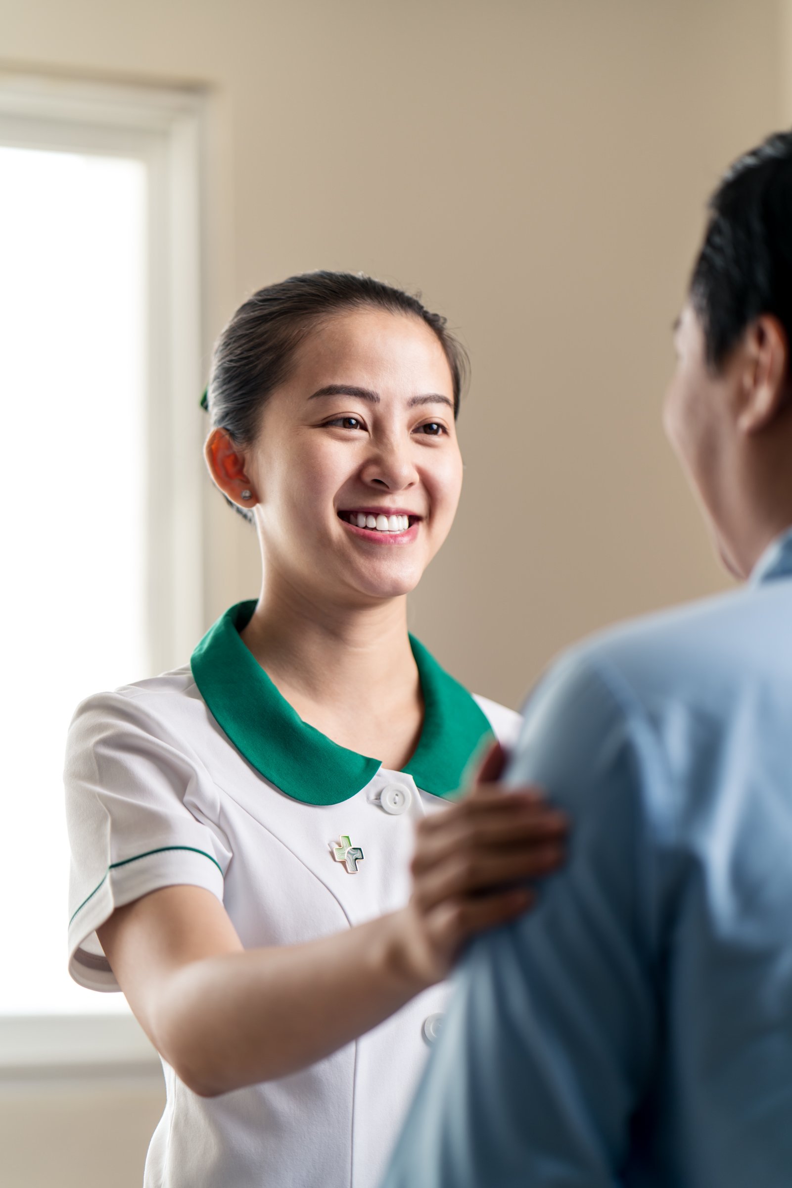 Female asian nurse smiling and comforting male patient.