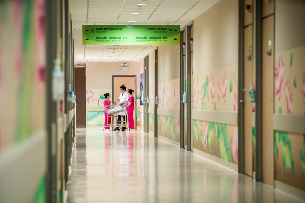 Doctors and Nurses discuss the health of a newborn baby in Hanh Phuc hospital maternity ward.