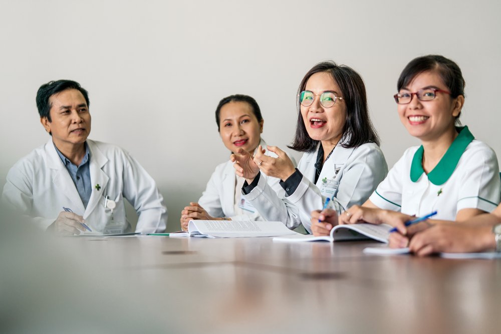 Doctors and nurses in discussion during boardroom meeting.