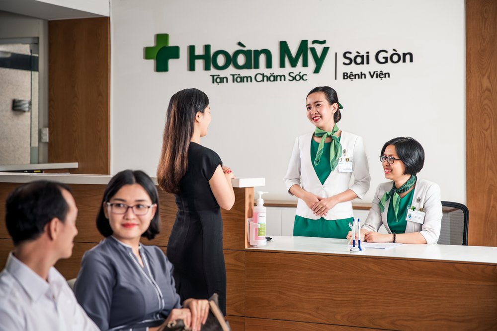Reception staff chat to patient at Hoan My Saigon Hospital reception desk.