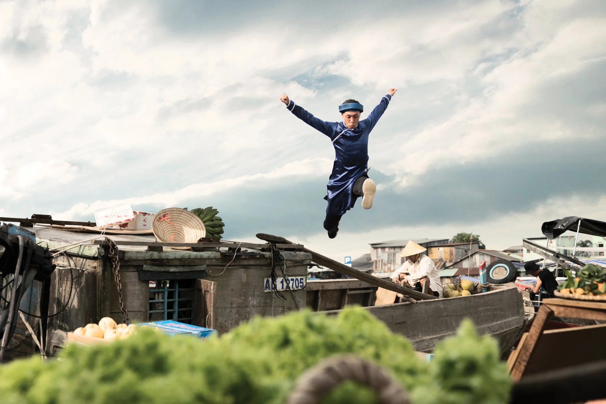  Groomsmen dressed in traditional Vietnamese wedding attire jumps between boat at the Cai Rang Floating market, Can Tho, Vietnam. 