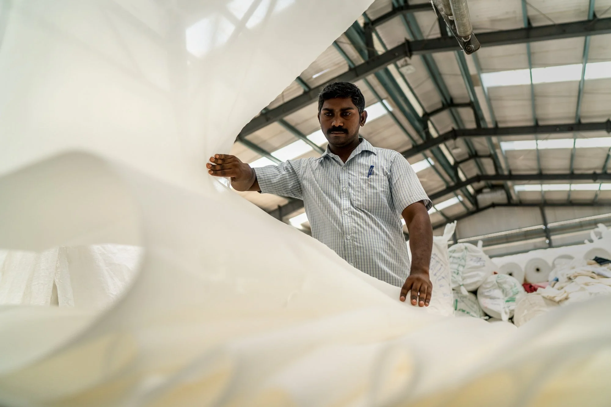  Indian worker folds fabric after it has been finished in textile factory. 